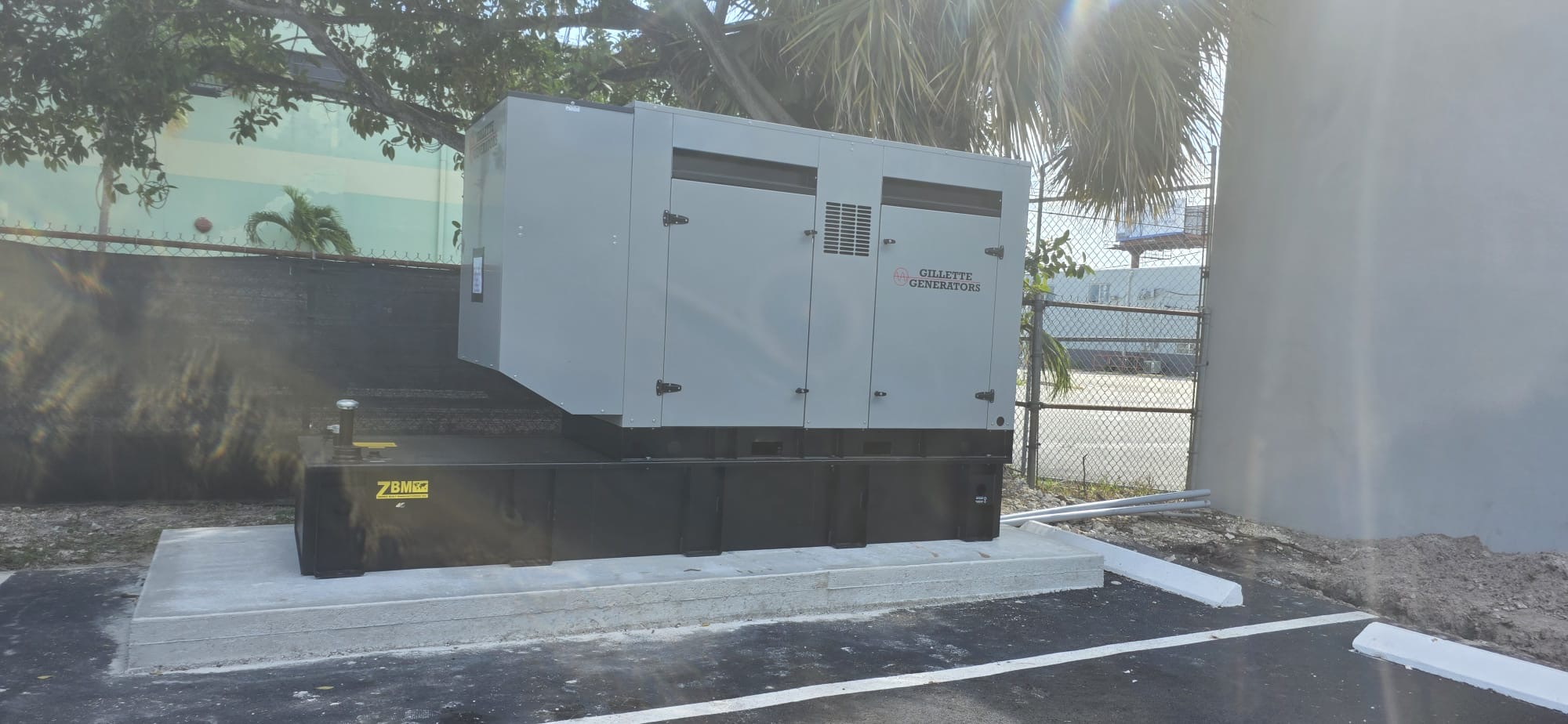 Gillette generator above a black base fuel tank beside a parking area.