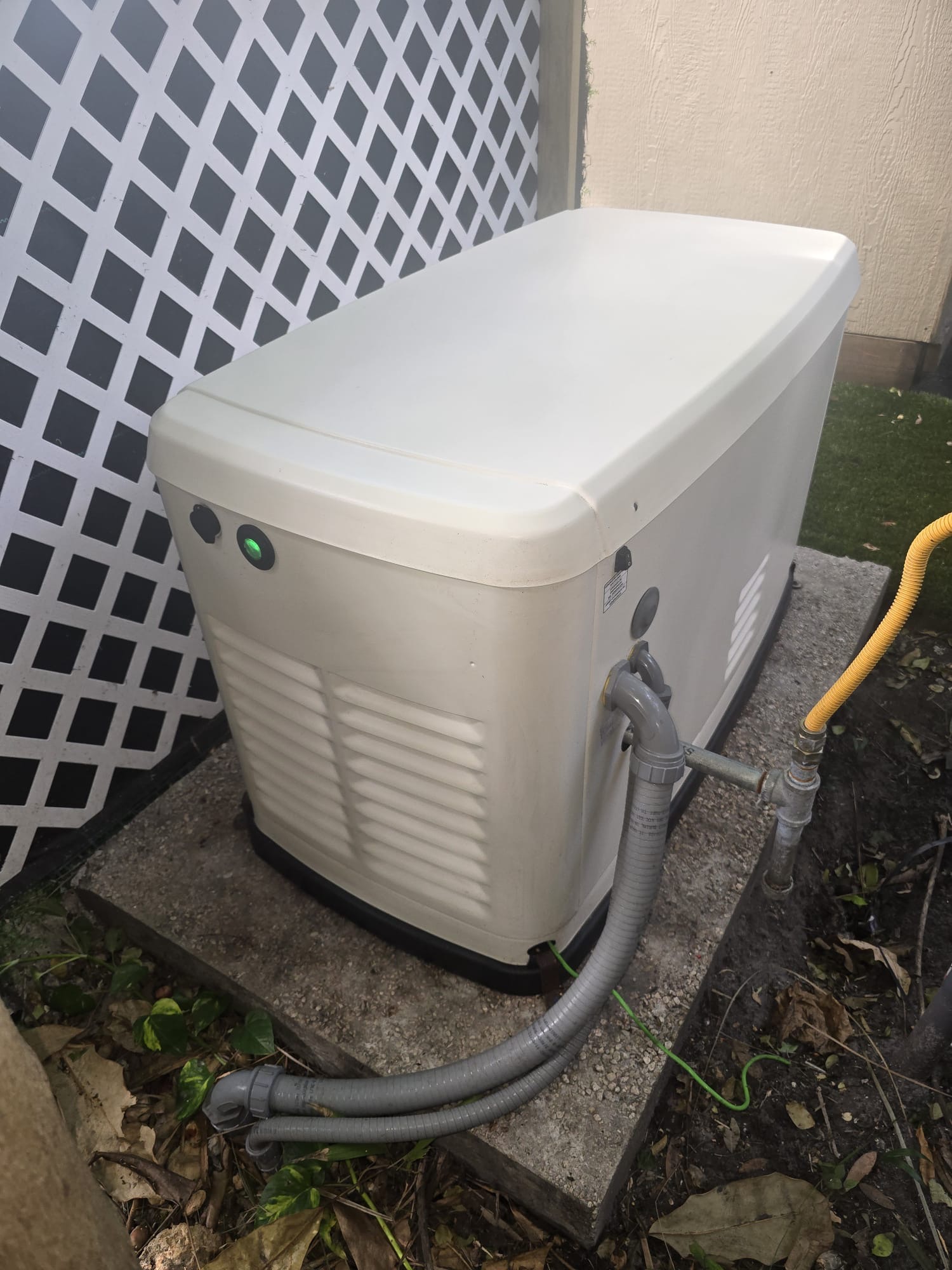Residential standby generator with visible electrical conduits and fuel connection.
