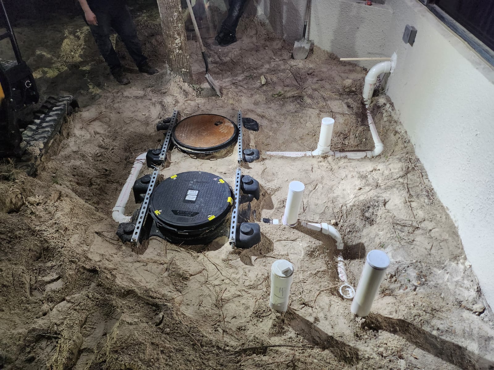 Grease trap installation with piping near building wall