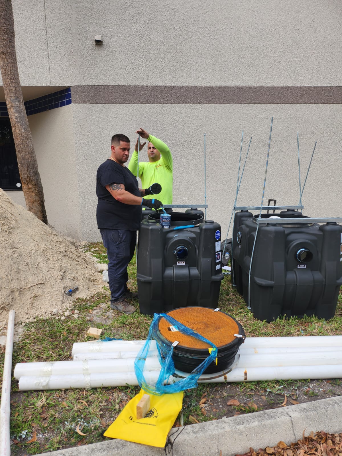 Workers preparing grease trap tanks and materials